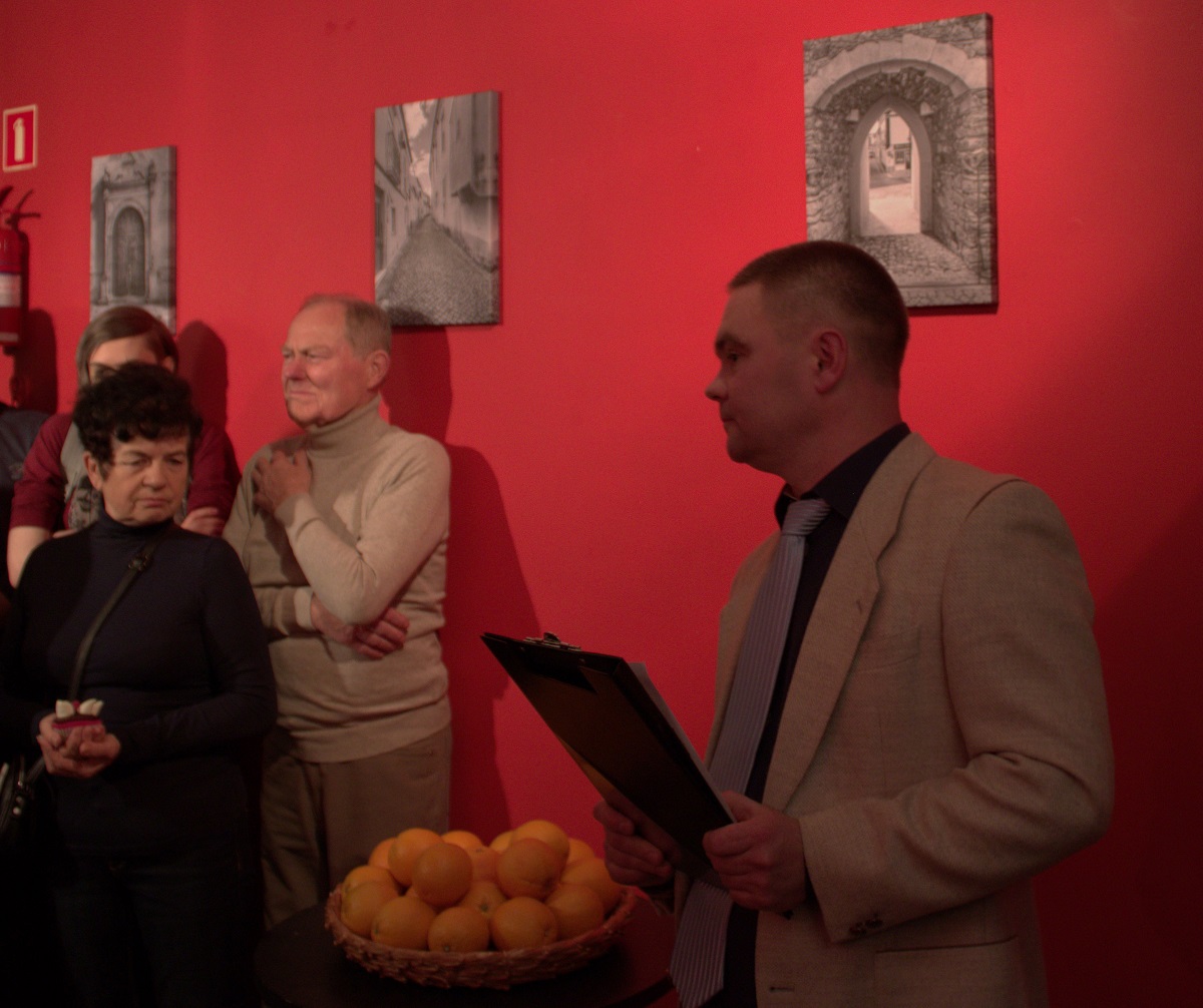 Autor jednej z wystaw fotograficznych i dwie osoby stojące na czerwonym tle