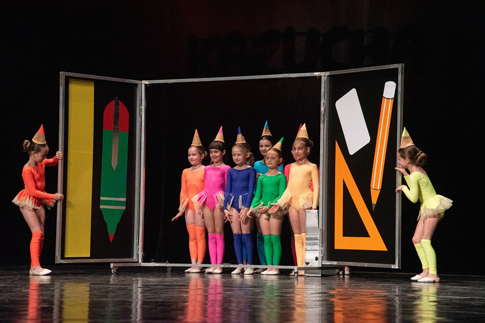 Tańczące dzieci w kolorowych strojach i czapeczkach