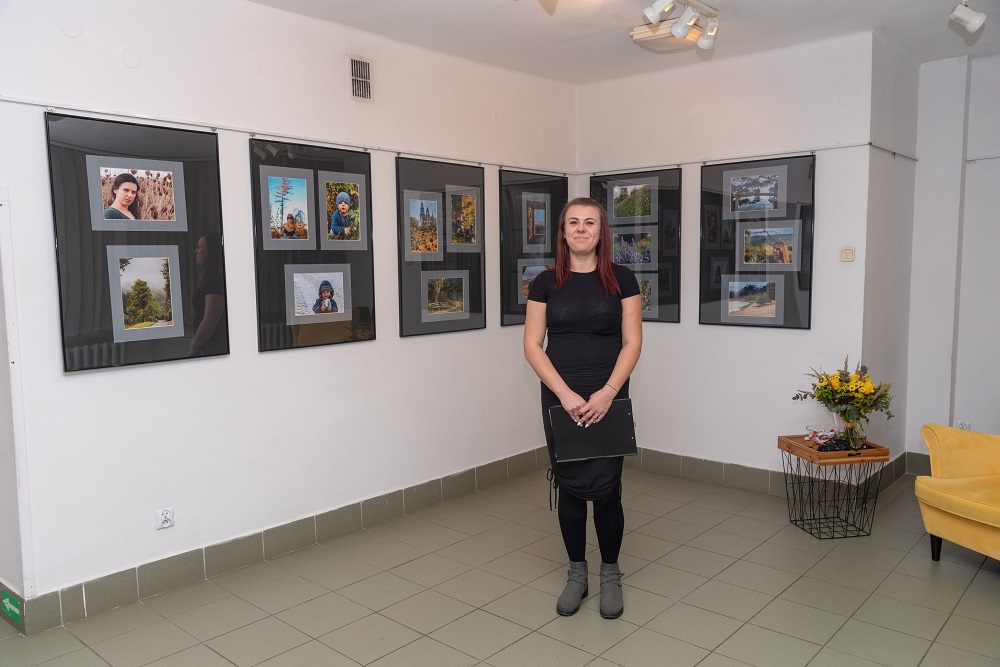 Słuchaczka Studium Monika Ostałowska stojąca na tle swojej wystawy fotograficznej