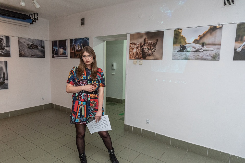 Słuchaczka Studium Izabela Kuśtek stojąca na tle swojej wystawy fotograficznej