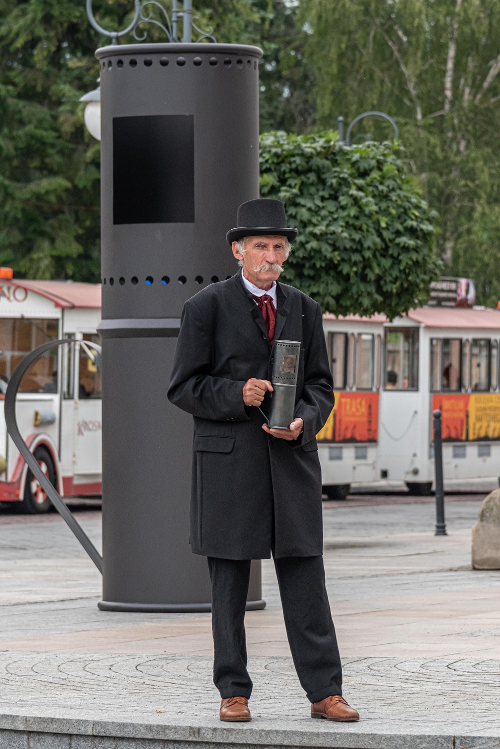 Mężczyzna w czarny, stroji i kapeluszy na tle dużej lampy naftowej