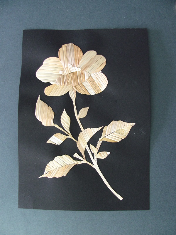 słomiane kwiaty przyklejone na czarnej kartce papieru