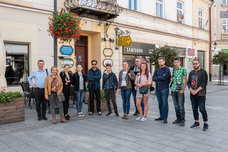 Grupa ludzi stojąca przed starą kamienicą w Rzeszowie