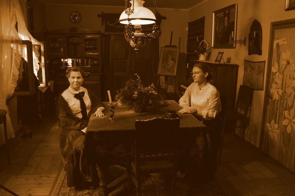 Kobiety w strojach szlacheckich siedzące przy stole