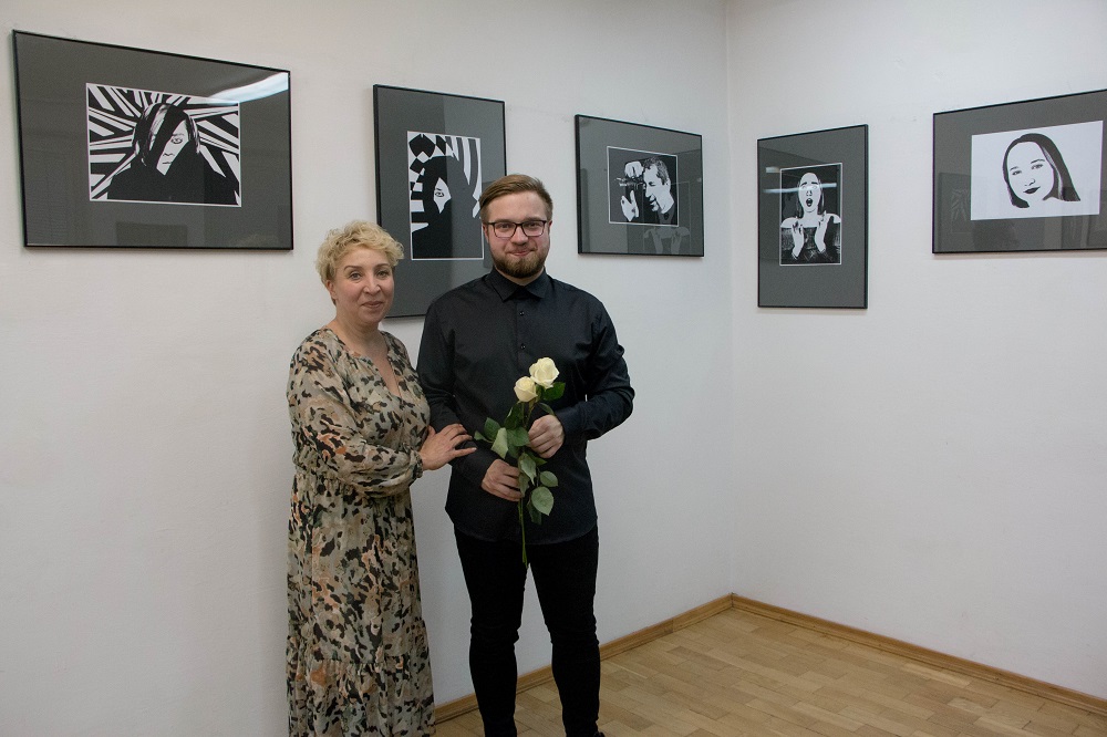 Na zdjęciu autor wystawy fotograficznej  Hubert Żak stojący na tle swoich zdjęć, które przedstawiają czarno białą grafikę. Obok autora stoi nauczycielka Lucyna Żak.
